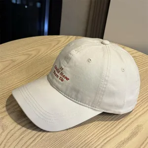 Detailansicht der lässigen, beige Baseballkappe mit brauner Stickerei an der Seite.
