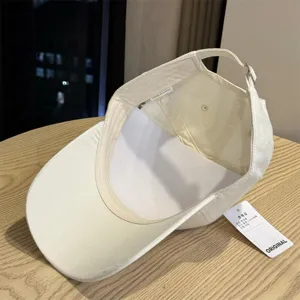 Detailansicht des beigen Baumwoll-Baseballcaps von innen, Verstellgurt und Etikett.
