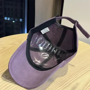 Detail view of purple baseball cap interior, showing adjustable strap and inner brand label.