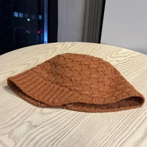 Close-up detail shot of a brown knitted winter beanie hat, showcasing soft texture and knit pattern.