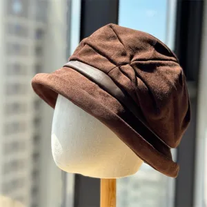 Detail shot of the brown faux suede bucket hat, showing the pleated texture and leather strap.