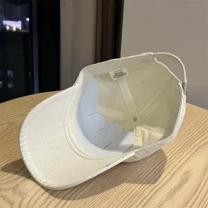 Detail view of a beige cotton baseball cap, showing interior label and structure clearly.