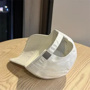 Detail view of the white cotton baseball cap featuring adjustable back strap and metal buckle.