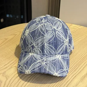 Blaues, gewaschenes Denim-Baseballcap mit weißer Blumenstickerei, breiter Schirm.