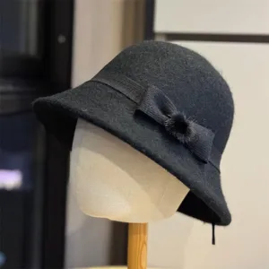 Classic black wool felt bucket hat featuring an elegant bow and fluffy fur ball decoration.