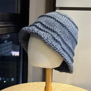 Close-up detail of the grey knitted bucket hat, showing the cozy textured pleated wool design.