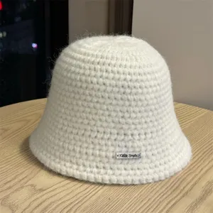 Gros plan d'un chapeau seau crocheté en tricot blanc douillet sur une table en bois.