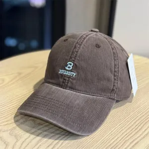 Brown washed cotton baseball cap detail, featuring embroidered B and necessity text logo.