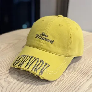 Detailed closeup view of the vintage washed yellow baseball cap featuring embroidered text.