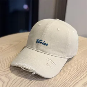 Beige distressed baseball cap with blue embroidered cursive text, soft top casual hat.