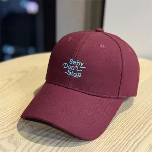 Burgundy baseball hat detail, blue embroidered letter design, casual cotton fabric cap.