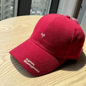Vue détaillée de la casquette de baseball en laine rouge avec lettrage brodé et visière courbée.