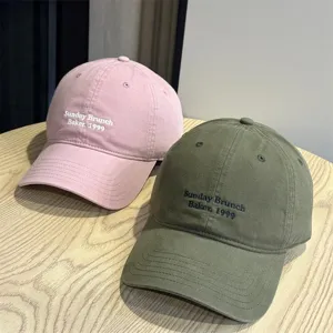 Detailed close-up shot of trendy soft-top embroidered baseball caps in pink and green.