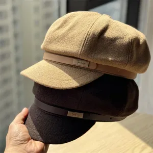 Detail view of classic woolen newsboy caps with leather strap in khaki and brown colors.