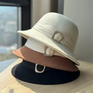 Close-up of stacked wool felt bucket hats with rhinestone buckle detail and elegant style.