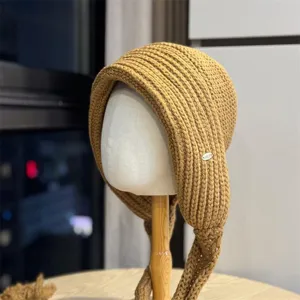 Detailansicht der warmen Winter-Strickmütze mit Ohrenklappen in Camel, gemütliche Textur.