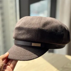 Detailed view of the brown woolen newsboy cap featuring a stylish leather strap and metallic accent.
