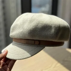 Woolen newsboy cap detail, beige retro beret with brown leather strap and metal buckle.