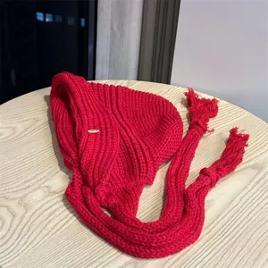 Rote gestrickte Mütze mit Ohrenklappen und langen Quasten, gemütliche Herbst- und Winterkopfbedeckung.