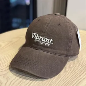 Detailed view of the dark brown baseball cap with white embroidered text and wide brim.