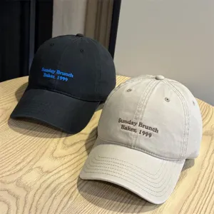 Detail view of casual cotton baseball caps in black and beige with stylish embroidered text.