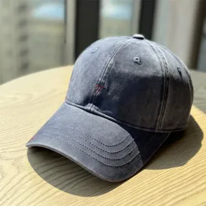 Close-up view of the washed grey baseball cap featuring red letter embroidery and fine brim stitching.
