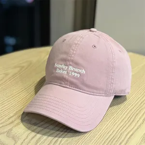 Pink cotton baseball cap detail, white letter embroidery Sunday Brunch Baker 1999, curved brim