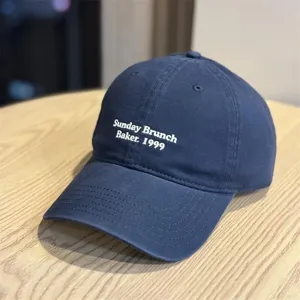 Detailed view of the navy blue cotton baseball cap featuring front white embroidery text.