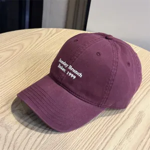 Close-up detail of the purple casual baseball cap with white letter embroidery design.