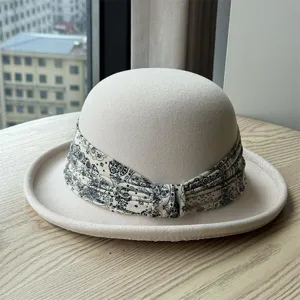 Close-up detail of beige wool felt cloche hat with stylish paisley pattern decorative band.