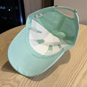 Close-up of mint green baseball cap interior, showing brand label and adjustable strap.