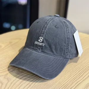 Detailed shot of dark grey washed cotton baseball cap with front letter embroidery.