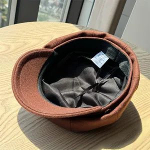 Detail view of the brown wool newsboy hat interior lining and wash label, autumn winter warm cap.