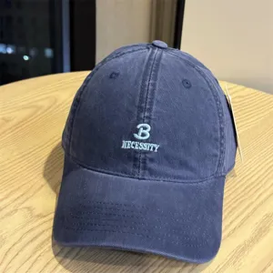 Close-up detail of the washed blue cotton baseball cap showcasing neat white letter embroidery.