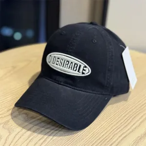 Detailed close-up of a black washed cotton baseball cap with embroidered lettering.