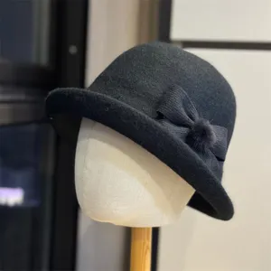 Zwarte pluche bucket hat detail, elegante strik, warme en stijlvolle winterhoofddeksel.