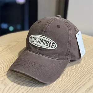 Detail shot of the vintage washed brown baseball cap with front oval embroidered letter logo.