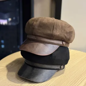 Λεπτομερής λήψη vintage καπέλων newsboy από καφέ και μαύρο σουέτ σε ξύλινο τραπέζι.
