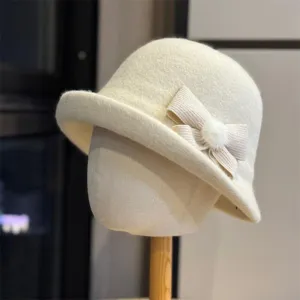 Gedetailleerde close-up van de elegante beige wintervissershoed met schattige gebreide strik en pompon.