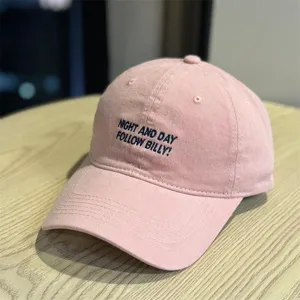 Pink washed cotton baseball cap with stylish embroidered text. Casual soft top hat for daily wear.