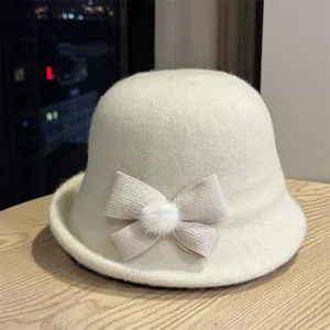 Close-up detail van de gezellige pluche bucket hat met gebreide strik en pompon.