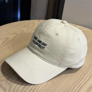 Vintage washed beige baseball cap featuring black embroidered text on the front crown.