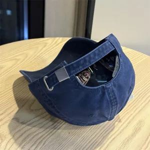 Detailed view of a vintage dark blue washed cotton baseball cap with metal buckle.