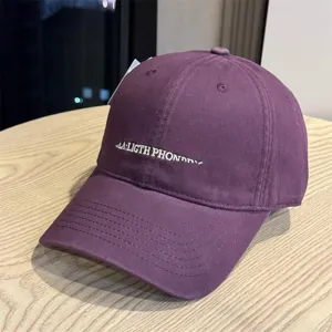 Detailansicht einer violetten Freizeit-Baseballkappe mit weißem Sticktext auf der Vorderseite.