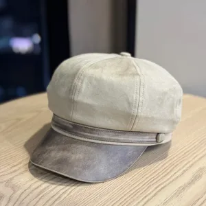 Λεπτομερές κοντινό πλάνο ενός vintage καπέλου newsboy από σουέτ με κομψή δερμάτινη γείσο.
