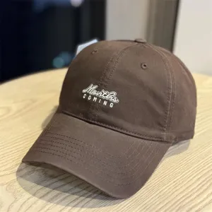 Detail view of the brown cotton baseball cap showing front letter embroidery and stitching.