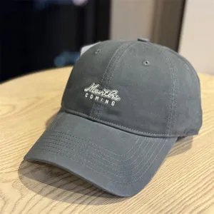 Detailed close-up of a stylish grey washed cotton baseball cap featuring front letter embroidery.
