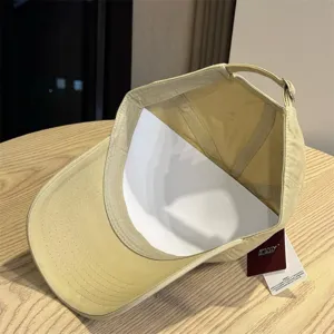Detailed shot of khaki washed distressed baseball cap showing soft top and brand tag design.