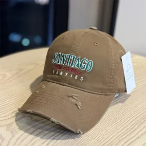 Brown distressed baseball cap detail, vintage washed cotton fabric with embroidered letters and brim rips.