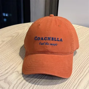 Detail view of the orange baseball cap featuring Coachella embroidery and soft cotton fabric.
